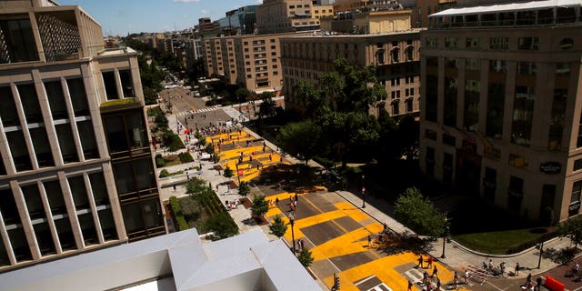 People walk on the words Black Lives Matter that was painted in bright yellow letters on 16th Street as demonstrators protest Sunday, June 7, 2020, near the White House in Washington, over the death of George Floyd. (AP Photo/Maya Alleruzzo)