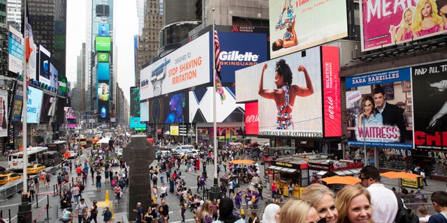 In this June 20, 2019, file photo, tourists visit Times Square in New York. After three months of a coronavirus crisis followed by protests and unrest, New York City is trying to turn a page when a limited range of industries reopen Monday, June 8, 2020. (AP Photo/Mark Lennihan, File)