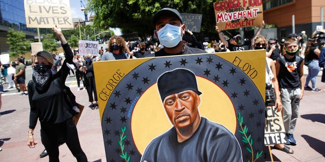 Artist Anthony Pittman holds an image of George Floyd Monday, June 8, 2020, in Los Angeles during a protest over the death of Floyd who died May 25 after he was restrained by Minneapolis police. (AP Photo/Marcio Jose Sanchez)