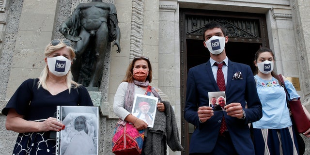 From left, Laura Capella, Nicoletta Bosica, Stefano Fusco and Arianna Dalba holds pictures of their relatives, victims of COVID-19, as they stand in front of Bergamo's court, Italy, June 10. Members of an association of relatives of COVID-19 victims filed a complaint with prosecutors seeking responsibility for the deaths of their loved ones. (AP Photo/Antonio Calanni)