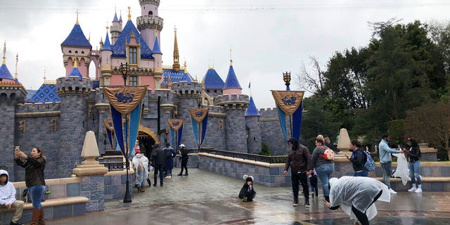 FILE: Visitors take photos at Disneyland in Anaheim, Calif.