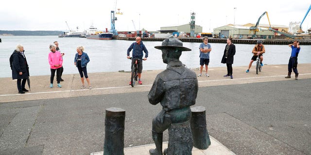 People look at the statue of the founder of the Scout movement Robert Baden-Powell on Poole Quay in Dorset, England ahead of its expected removal to "safe storage" following pressure to remove it over concerns about his alleged actions while in the military and "Nazi sympathies" Thursday June 11, 2020. (Andrew Matthews/PA via AP)