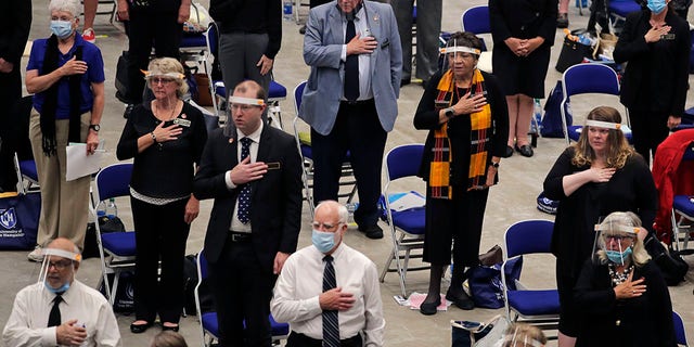 Members of the New Hampshire House of Representatives stand for the Pledge of Allegiance at the start of their session in Durham, N.H. on Thursday, June 11, 2020, at the Whittemore Center at the University of New Hampshire. The Legislature, which suspended its work in March because of the COVID-19 virus outbreak, gathered at the arena for the first House session held outside the Statehouse since the Civil War. (AP Photo/Charles Krupa)