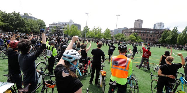 Cyclists raise their fists as they gather at Cal Anderson Park after taking part in the 