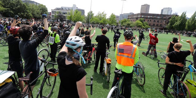 Cyclists raise their fists as they gather at Cal Anderson Park after taking part in the "Ride for Justice," Thursday, June 11, 2020, Seattle. People rode to the park and then took part in a rally to protest against police brutality and racial inequality.
