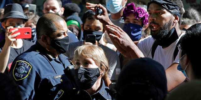A protester talks with Seattle Police assistant chiefs Adrian Diaz, left, and Deanna Nollette, center, inside what is being called the "Capitol Hill Autonomous Zone" in Seattle.