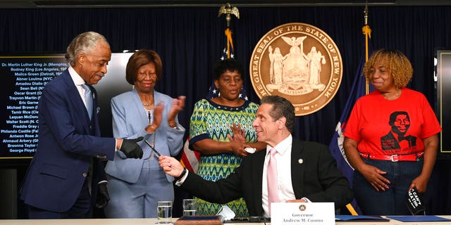 New York Governor Andrew M. Cuomo, center, hands a pen to Rev. Al Sharpton after signing into law, Friday, June 12, 2020, in New York, a sweeping package of police accountability measures that received new backing following protests of George Floyd's killing. (Kevin P. Coughlin, Office of New York Governor Andrew M. Cuomo via AP)