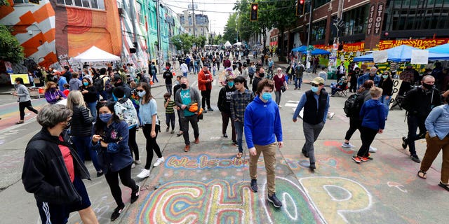 Visitors walk near a sign that reads "Welcome to CHOP," Sunday, June 14, 2020, inside what has been named the Capitol Hill Occupied Protest zone in Seattle. . (AP Photo/Ted S. Warren)