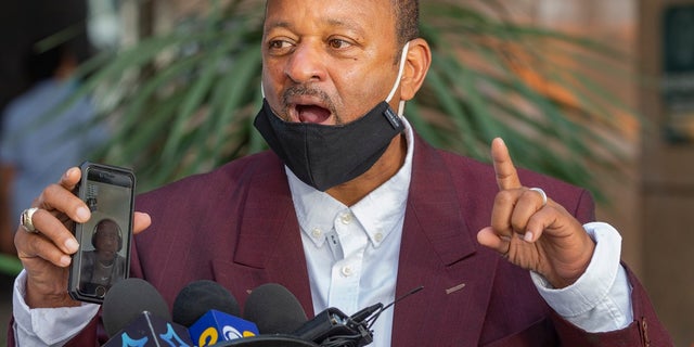 Activist Najee Ali speaks as he was calling for an independent investigation in the deaths of both Robert Fuller and Malcolm Harsch, at a news conference outside the Ronald Reagan State building in Los Angeles on Monday, June 15, 2020. State and federal authorities will monitor the investigation into the death of Fuller, a black man found hanging from a tree in the Southern California city of Palmdale, officials said Monday following large weekend protests. Ali was holding a cellphone while video conferencing with De'Avery Richardson, the brother of Harsch, giving a remote video statement. (AP Photo/Damian Dovarganes)
