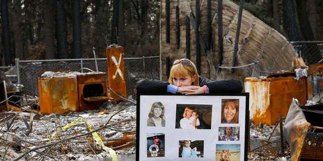 FILE: Christina Taft, the daughter of Camp Fire victim Victoria Taft, displays a collage of photos of her mother, at the burned-out ruins of the Paradise, Calif.