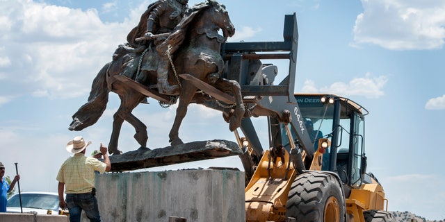 Rio Arriba County workers remove the bronze statue of Spanish conqueror Juan de Oñate from its pedestal in front of a cultural center in Alcalde, N.M., Monday, June 15, 2020. Crowds of people for and against the removal lined Highway 68 near the center. (Eddie Moore/The Albuquerque Journal via AP)