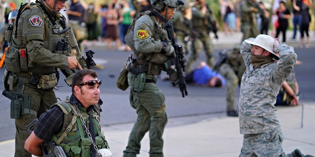 Albuquerque police detain members of the New Mexico Civil Guard, an armed civilian group, following the shooting of a man during a protest over a statue of Spanish conquerer Juan de Oñate on Monday, June 15, 2020, in Albuquerque, N.M. (Adolphe Pierre-Louis/The Albuquerque Journal via AP)