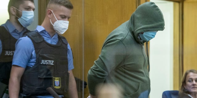 Police officers lead defendant Markus H., right, into the court room in Frankfurt, German, June 16, 2020. The Higher Regional Court begin hearing the case against two far-right extremists accused of killing the regional politician Walter Luebcke of Merkel"s Christian Democratic Union party. (Thomas Lohnes/Pool via AP)