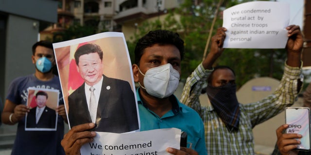 A man holds a photograph of Chinese President Xi Jinping during a protest in Ahmedabad, India, June 16, 2020, after Indian soldiers were killed in a deadly border clash with Chinese forces. (AP Photo/Ajit Solanki)