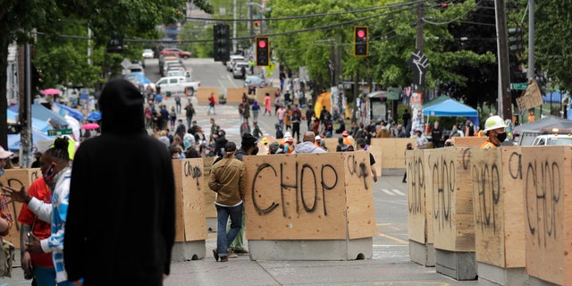 New cement and wood barricades bear the name CHOP, Tuesday, June 16, 2020, inside what has been named the Capitol Hill Occupied Protest zone in Seattle. The city put the barriers in place Tuesday in hopes of defining an area where emergency, delivery, and other vehicles can travel through the area while still preserving space for protesters, who have been there since police pulled back from near the department's East Precinct after recent clashes with people protesting the death of George Floyd. (AP Photo/Ted S. Warren)