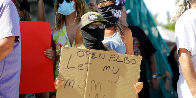 Bartender Kat DeLaTorre stands with her son Nico, 12, during a "Right to Work" rally outside of the Elbo Room bar, which remains closed, during the new coronavirus pandemic, June 16, in Fort Lauderdale, Fla.