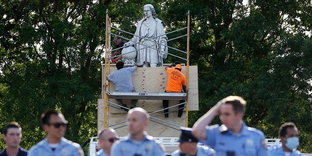 City workers cover the statue of Christopher Columbus at Marconi Plaza, Tuesday, June 16, 2020, in the South Philadelphia neighborhood of Philadelphia. (AP Photo/Matt Slocum)