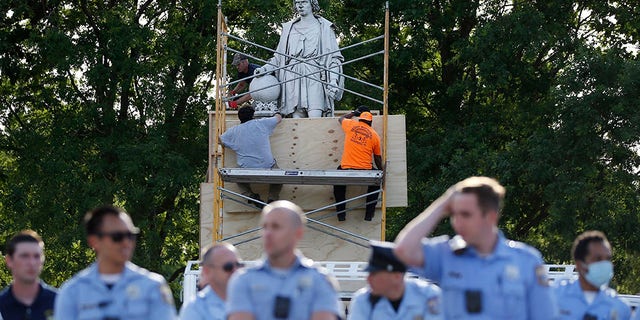 City workers cover the statue of Christopher Columbus at Marconi Plaza, Tuesday, June 16, 2020, in the South Philadelphia neighborhood of Philadelphia. (AP Photo/Matt Slocum)