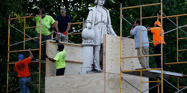 City worker cover the statue of Christopher Columbus at Marconi Plaza, Tuesday, June 16, 2020, in the South Philadelphia neighborhood of Philadelphia. (AP Photo/Matt Slocum)