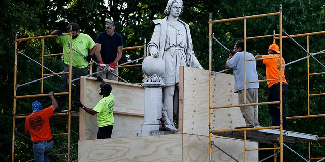 City worker cover the statue of Christopher Columbus at Marconi Plaza, Tuesday, June 16, 2020, in the South Philadelphia neighborhood of Philadelphia. (AP Photo/Matt Slocum)