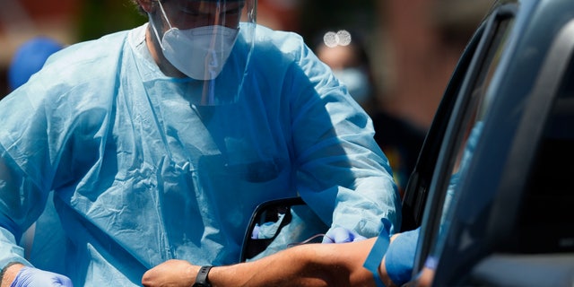 A health worker draws blood for COVID-19 antibody testing in Dearborn, Mich on June 12, 2020. A genetic analysis of COVID-19 patients published Wednesday the New England Journal of Medicine suggests a person's blood type may have some influence on whether they develop severe disease. (AP Photo/Paul Sancya, File)