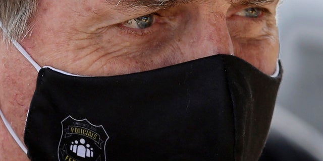In this May 26, 2020 file photo, Brazil's President Jair Bolsonaro, wearing a face mask with a logo of the Federal Police, leaves his official residence of Alvorada Palace in Brasilia, Brazil. (AP Photo/Eraldo Peres, FIle)