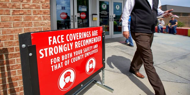 A man wearing a face mask exits the Sarpy County administration building in Papillion, Neb., on Thursday, June 18, 2020, where face covering is recommended but not mandatory. (AP Photo/Nati Harnik)