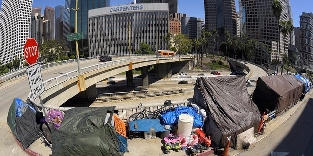 This file photo shows a homeless encampment at the corner of Wilshire Boulevard and Beaudry Avenue along the 110 Freeway during the coronavirus outbreak in downtown Los Angeles. A judge has approved an agreement in which the city and county of Los Angeles will provide housing for almost 7,000 homeless people who live near freeways. (AP Photo/Mark J. Terrill, File)