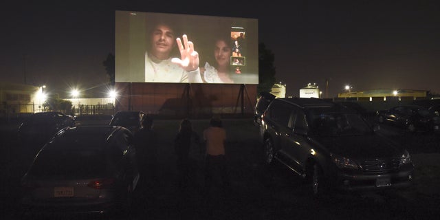 Dave Franco, left, director/co-writer of "The Rental," and his wife, cast member Alison Brie, are seen on a movie screen as they take part in a Zoom Q&A session from their car following an advance screening of the film at the Vineland Drive-In, Thursday, June 18, 2020, in City of Industry, Calif. (AP Photo/Chris Pizzello)