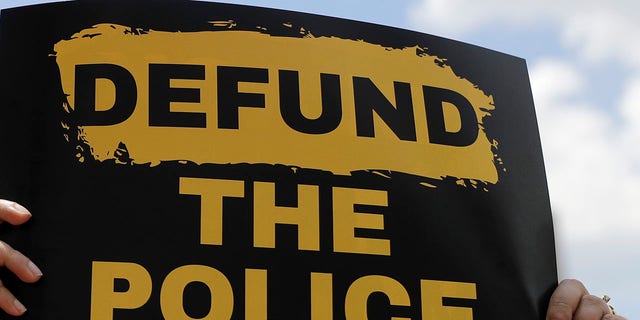 A person holds up a defund the police sign