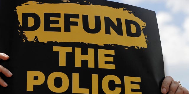 A person holds up a defund the police sign