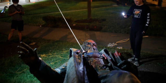 People film the only statue of a Confederate general, Albert Pike, in the nation's capital after it was toppled by protesters and set on fire in Washington early Saturday, June 20, 2020. It comes on Juneteenth, the day marking the end of slavery in the United States, amid continuing anti-racism demonstrations following the death of George Floyd in Minneapolis.(AP Photo/Maya Alleruzzo)