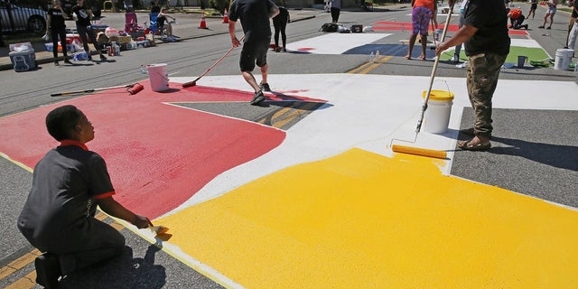 Local artists paint "Black Lives Matter" spanning three blocks on East 93rd Street in Cleveland, on Saturday. (John Kuntz/Cleveland.com via AP)