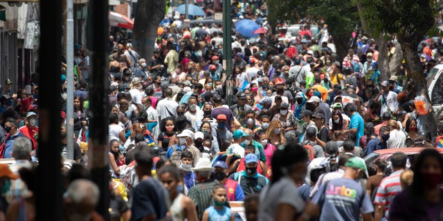 People, some wearing face masks as a measure to curb the spread of the new coronavirus, walk in the Catia neighborhood of Caracas, Venezuela, Saturday, June 20, 2020, during a relaxation of restrictive measures amid the new coronavirus pandemic. (AP Photo/Ariana Cubillos)