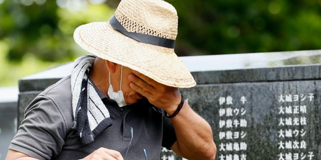 A man cries as he visits "Cornerstone of Peace" monument walls on which the names of all those who lost their lives, both civilians and military of all nationalities in the Battle of Okinawa are engraved, at the Peace Memorial Park in Itoman, Okinawa, Japan, Tuesday, June 23, 2020. (Kyodo News via AP)