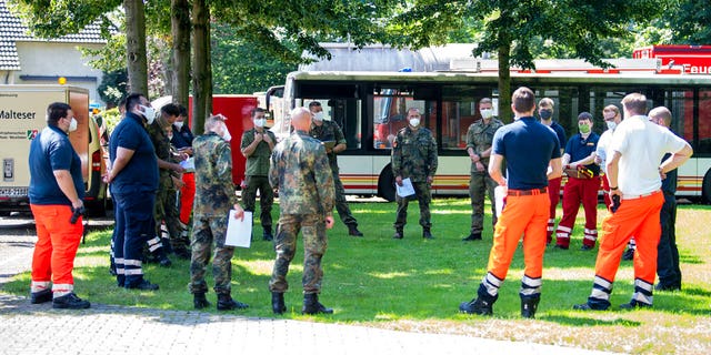 Mobile teams testing people on the coronavirus are instructed on a meadow of a fire station in Rheda-Wiedenbrueck, Germany, Tuesday, June 23, 2020 . The mobile teams from the German Federal Armed Forces and aid organizations are formed to visit and test people in quarantine throughout the Guetersloh region. (David Inderlied/dpa via AP)