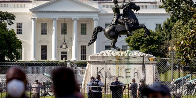The White House is visible behind a statue of President Andrew Jackson in Lafayette Park on Tuesday in Washington, with the word "Killer" spray-painted on its base. Protesters tried to topple the statue Monday night. (AP Photo/Andrew Harnik)