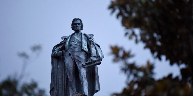 A 100-foot monument to former U.S. vice president and slavery advocate John C. Calhoun towers over a downtown square Tuesday, June 23, 2020, in Charleston, S.C. Officials in Charleston voted unanimously Tuesday to remove the statue from a downtown square, the latest in a wave of actions arising from protests against racism and police brutality against African Americans. (AP Photo/Meg Kinnard)