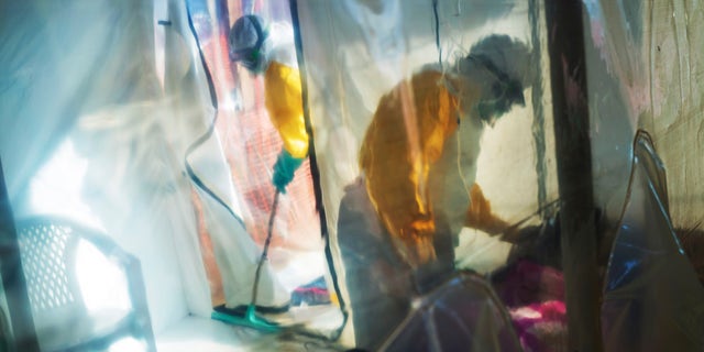 FILE - In this Saturday, July 13, 2019 file photo, health workers wearing protective suits tend to an Ebola victim kept in an isolation tent in Beni, Congo. AP Photo/Jerome Delay, File)