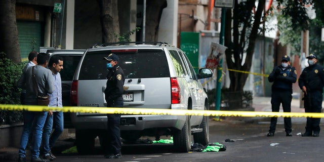 An abandoned vehicle that is believed to have been used by gunmen in an attack against Mexico City's chief of police is sealed off with yellow tape and guarded by responding officers on June 26. Heavily-armed gunmen attacked and wounded Omar Garcia Harfuch in a brazen operation that left an unspecified number of dead, Mayor Claudia Sheinbaum said. (AP)
