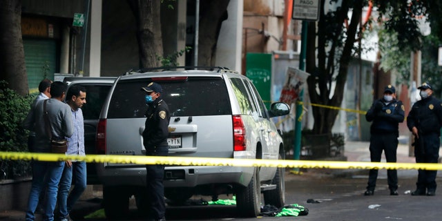 An abandoned vehicle that is believed to have been used by gunmen in an attack against Mexico City's chief of police is sealed off with yellow tape and guarded by responding officers on June 26. Heavily-armed gunmen attacked and wounded Omar Garcia Harfuch in a brazen operation that left an unspecified number of dead, Mayor Claudia Sheinbaum said. (AP)