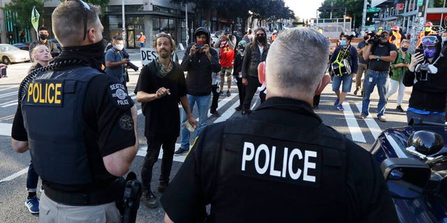 Seattle police officers confront protesters Friday, June 26, 2020 just outside a barricade in the Capitol Hill Occupied Protest (CHOP) area in Seattle after Seattle Department of Transportation workers arrived with the intention of remove the barricades that had been established in the area, which has been occupied by protesters since Seattle police withdrew from their East Precinct building after violent clashes with protesters earlier this month.