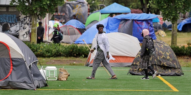 People walk among tents in a city park Sunday, June 28, 2020, in Seattle, where several adjacent streets are blocked off in what has been named the Capitol Hill Occupied Protest zone. Seattle Mayor Jenny Durkan met with demonstrators Friday after some lay in the street or sat on barricades to thwart the city's effort to dismantle the protest zone that has drawn scorn from President Donald Trump and a lawsuit from nearby businesses. (AP Photo/Elaine Thompson)