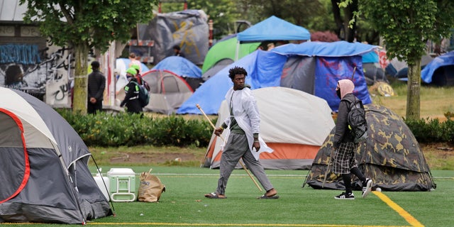 People walk among tents in a city park Sunday, June 28, 2020, in Seattle, where several adjacent streets are blocked off in what has been named the Capitol Hill Occupied Protest zone. Seattle Mayor Jenny Durkan met with demonstrators Friday after some lay in the street or sat on barricades to thwart the city's effort to dismantle the protest zone that has drawn scorn from President Donald Trump and a lawsuit from nearby businesses. (AP Photo/Elaine Thompson)