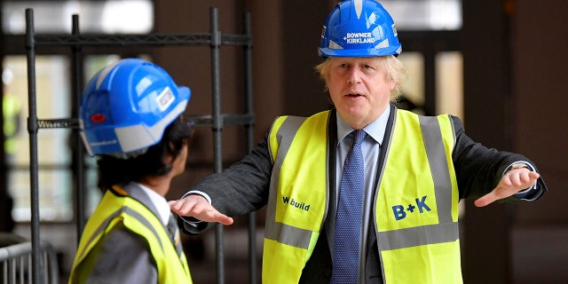 Britain's Prime Minister Boris Johnson talks with year 10 pupil Vedant Jitesh during a visit to the construction site of Ealing Fields High School in west London, Monday June 29, 2020. (Toby Melville/Pool via AP)