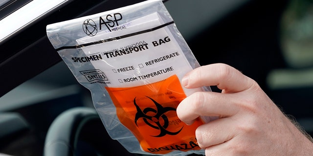 A patient returns his testing sample at a self-collection COVID-19 testing site June 29, in Houston. COVID-19 cases continue to surge across Texas. (AP Photo/David J. Phillip)