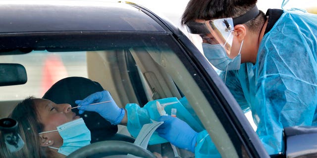 In this June 27, 2020, photo, people are tested in their in vehicles in Phoenix's western neighborhood of Maryvale in Phoenix for free COVID-19 tests organized by Equality Health Foundation, which focuses on care in underserved communities. 