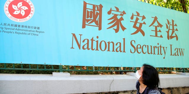 A woman walks past a promotional banner of the national security law for Hong Kong, in Hong Kong, Tuesday, June 30, 2020. China has approved a contentious law that would allow authorities to crack down on subversive and secessionist activity in Hong Kong, sparking fears that it would be used to curb opposition voices in the semi-autonomous territory. 