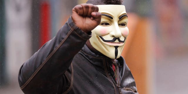 A protester raises his fist as he wears a Guy Fawkes mask near the Seattle Police Department East Precinct building, Tuesday, June 30, 2020 at the CHOP (Capitol Hill Occupied Protest) zone in Seattle.