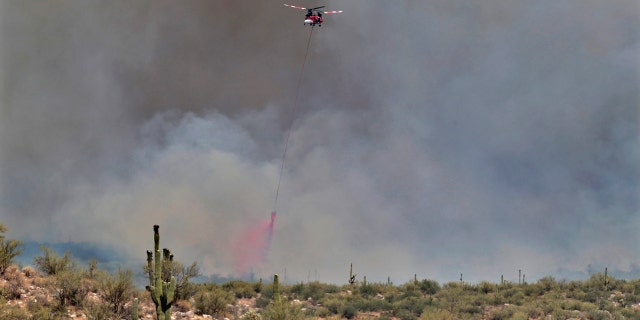 A wildfire air attack crew crew douses the Sonoran Desert filled with saguaro cacti with retardant during the Bighorn Fire Friday, June 12, 2020, in Oro Valley, Ariz.